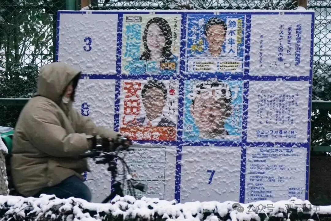 2月8日,东京雪花纷飞,行人骑车经过街头的选举广告牌。(来源:法新社)